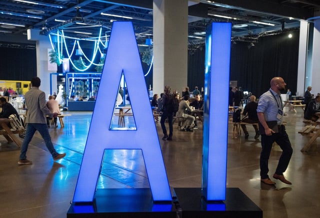 People walk past an AI sign at the All In artificial intelligence conference, Thursday, Sept. 28, 2023, in Montreal. THE CANADIAN PRESS/Ryan Remiorz