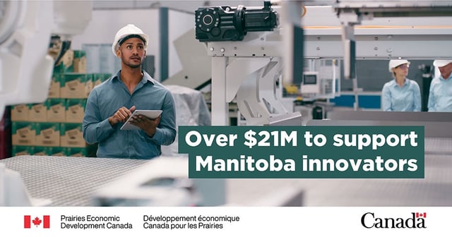 A man wearing a hard hat is standing next to some manufacturing equipment while typing on a tablet. Text: “Over $21M to support Manitoba innovators”.