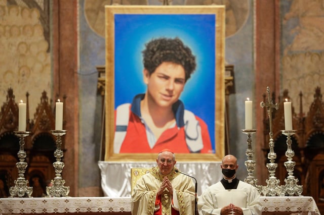 ARCHIVO - Una imagen de Carlo Acutis, un muchacho italiano que murió de leucemia en 2016 a los 15 años, durante su ceremonia de beatificación oficiada por el cardenal Agostino Vallini, al centro, en la Basílica de San Francisco, en Asís, Italia, el 10 de octubre de 2020. (AP Foto/Gregorio Borgia, Archivo)