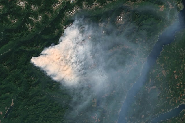 Satellite view of the Bear Gulch Fire shows a dense smoke plume over Mason County, Washington, as crews battle the wildfire burning over 7,000 acres in Olympic National Forest and Park. Responders are prioritizing evacuations, air quality protection, and structure defense amid challenging terrain and heavy smoke. Imaged 12 August 2025.