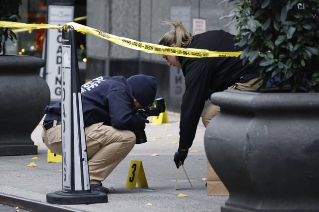 FILE - Members of the New York police crime scene unit photograph bullets lying on the sidewalk as they investigate the scene outside the Hilton Hotel in midtown Manhattan where Brian Thompson, the CEO of UnitedHealthcare, was fatally shot, Dec. 4, 2024, in New York. (AP Photo/Stefan Jeremiah, File)