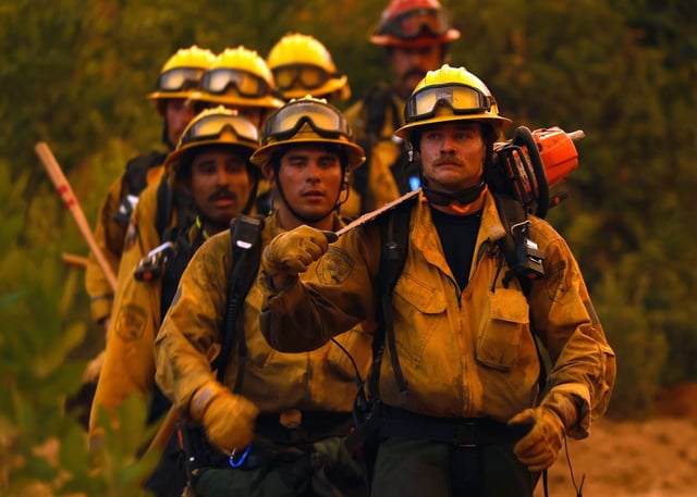 Cal Fire firefighters walk down a dozer line while battling the Pickett Fire on August 21, 2025 in Calistoga, California. The Pickett fire has burned over 1,200 acres in the Napa Valley and is zero percent contained.