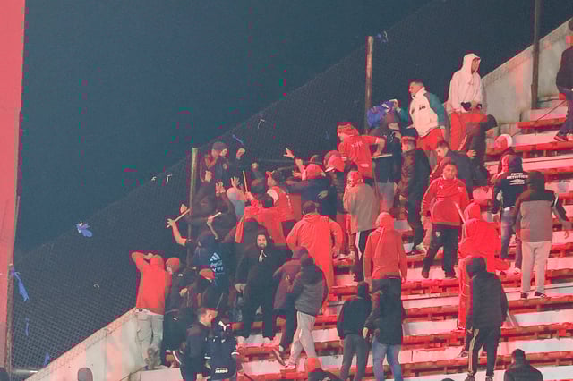 Barrabravas de Independiente atacan a hinchas de Universidad de Chile que se guarecen detrás del alambrado, con el vacío por debajo; Gonzalo Alfaro cayó varios metros y se lastimó gravemente.