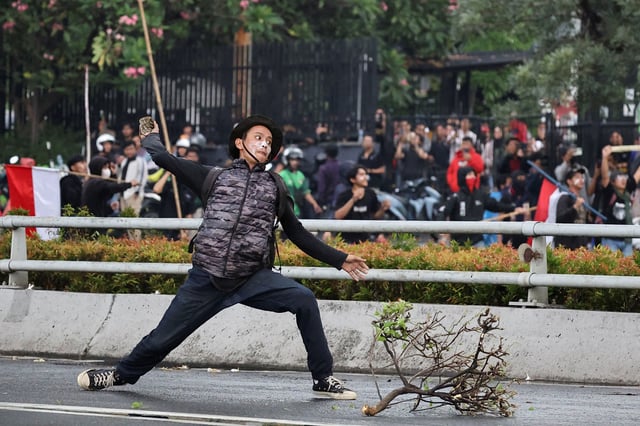 A demonstrator throws a stone towards the police during a protest against what the demonstrators say are exorbitant allowances for Indonesian parliament members, outside Indonesian parliament buildings in Jakarta, Indonesia, August 28, 2025. REUTERS/Willy Kurniawan