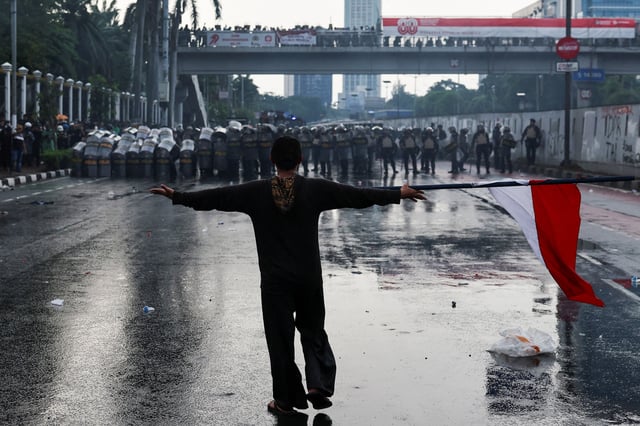 A demonstrator carrying an Indonesian flag gestures to riot police during a clash at a protest against what the demonstrators say are exorbitant allowances for Indonesian parliament members, outside Indonesian parliament buildings in Jakarta, Indonesia. REUTERS/Willy Kurniawan