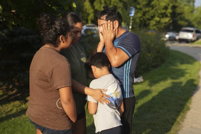 A family stands outside Annunciation Catholic Church after Wednesday's school shooting, Thursday, Aug. 28, 2025, in Minneapolis. (AP Photo/Abbie Parr)