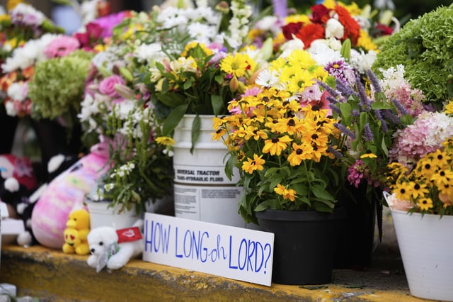 A sign stands amid flowers at a memorial at Annunciation Catholic Church after Wednesday's school shooting, Thursday, Aug. 28, 2025, in Minneapolis. (AP Photo/Abbie Parr)