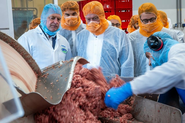 Alois Rainer steht mit Hygeneschutz vor einem offenen Cutter mit ordentlich Fleisch beim Betriebsrundgang im Unternehmen Ludwigsluster Fleisch- und Wurstwaren