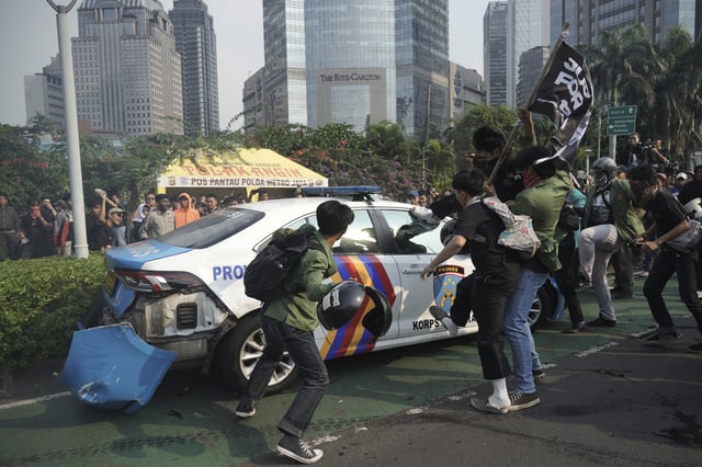 Students attack a police car during a protest following the death of a delivery rider who was run over by a police armored vehicle in a rally against lawmakers' privilege, in Jakarta, Indonesia, Friday, Aug. 29, 2025. (AP Photo/Tatan Syuflana)