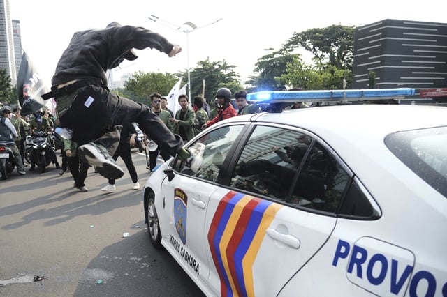 A student attacks a police car during a protest following the death of a delivery rider who was run over by a police armored vehicle in a rally against lawmakers' privilege, in Jakarta, Indonesia, Friday, Aug. 29, 2025. (AP Photo/Tatan Syuflana)