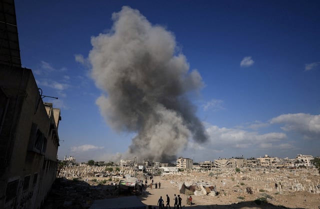 Palestinians gather near a cemetery as smoke rises following an explosion during an Israeli operation in Gaza City, August 28, 2025. REUTERS/Dawoud Abu Alkas/File Photo