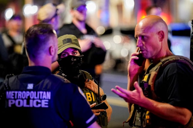 FILE PHOTO: Members of the Federal Bureau of Investigation (FBI) confer with a Metropolitan Police Department office during a traffic stop, after U.S. President Donald Trump deployed National Guard and ordered an increased presence of federal law enforcement to assist in crime prevention, in Washington, D.C., U.S., August 17, 2025. REUTERS/Al Drago/File Photo