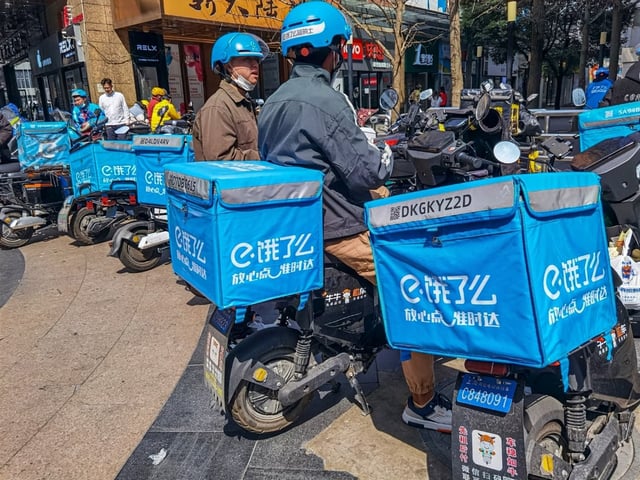 Ele.me food delivery riders wait for orders on a street in Beijing. Photo: Shutterstock