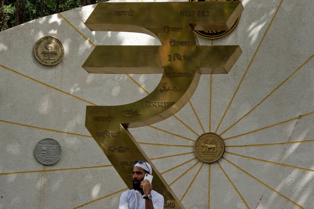 A man speaks on his mobile phone next to an installation of the Rupee logo and Indian currency coins outside the Reserve Bank of India (RBI) headquarters in Mumbai, India, August 1, 2025. REUTERS/Hemanshi Kamani/File Photo