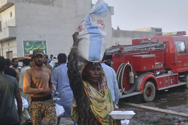 A woman carries sack of food items as she walks back after getting it from a relief-camp set up by Pakistan army for flood victims on the outskirts of Sodhra town, in Wazirabad district, Pakistan, Aug. 28, 2025. (AP Photo/A. Rizvi)