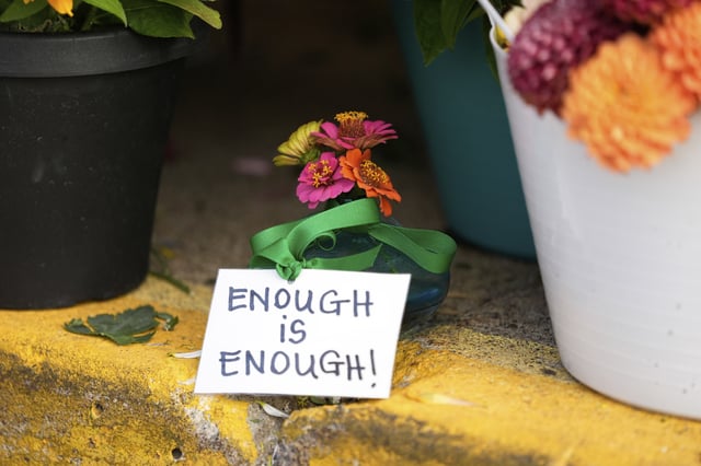 A sign stands amid flowers at a memorial at Annunciation Catholic Church after Wednesday's school shooting, Thursday, Aug. 28, 2025, in Minneapolis. (AP Photo/Abbie Parr)