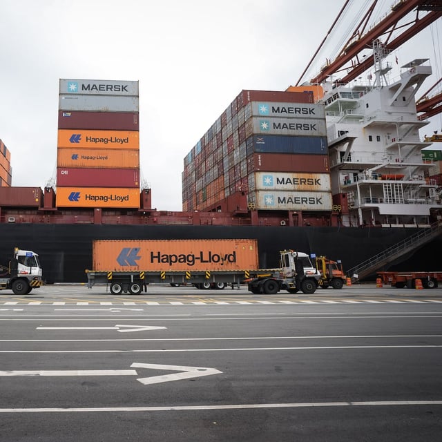 Transport trucks carry cargo containers to be loaded on the Hapag-Lloyd container ship Frankfurt Express at the DP World Centerm terminal at port, in Vancouver, on Sunday, August 3, 2025. THE CANADIAN PRESS/Darryl Dyck