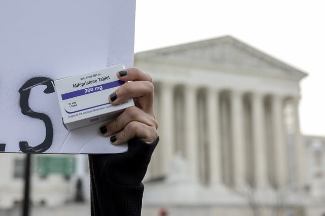 FILE - An abortion-rights activist holds a box of mifepristone pills as demonstrators from both anti-abortion and abortion-rights groups rally outside the Supreme Court in Washington, on March 26, 2024. (AP Photo/Amanda Andrade-Rhoades, File)