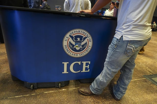 A person checks a cell phone while waiting to talk to representatives during an ICE, Immigration and Customs Enforcement, hiring fair Tuesday, Aug. 26, 2025, in Arlington, Texas. (AP Photo/Julio Cortez)