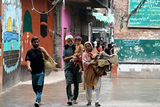 Des habitants dont les maisons ont été submergées par les eaux en crue du fleuve Ravi arrivent dans une école publique servant de refuge temporaire à Shahdara, le 29 août 2025 au Pakistan