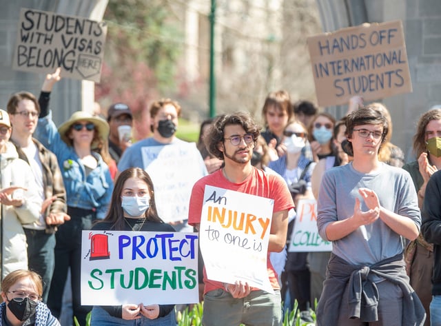 Demonstrators hold signs at a rally at the Sample Gates for international graduate student rights on Thursday, April 10, 2025.