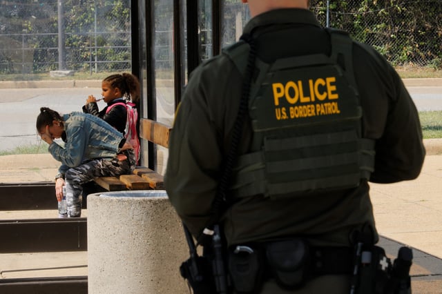 Passengers wait for a bus at Anacostia Station in Washington, D.C., while a U.S. Border Patrol agent looks on.