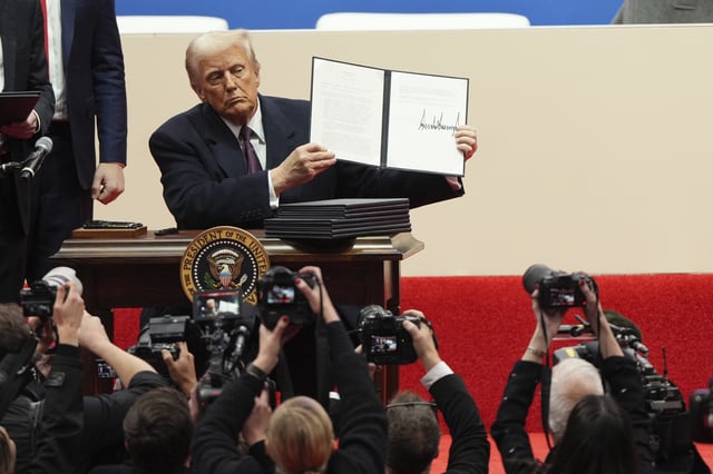FILE - President Donald Trump holds up an executive order after signing it at an indoor Presidential Inauguration parade event in Washington, Jan. 20, 2025. (AP Photo/Matt Rourke, File)