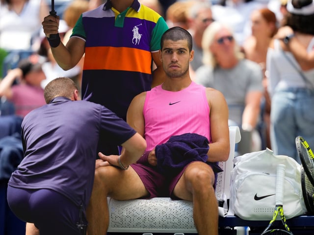 A trainer works on Carlos Alcaraz, of Spain, during a medical timeout in the second set against Luciano Darderi, of Italy, during the third round of the U.S. Open tennis championships, Friday, Aug. 29, 2025, in New York. (AP Photo/Yuki Iwamura)