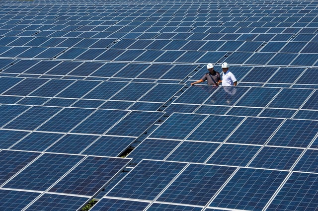 State Electricity Company officials stands between solar cell panels at the largest solar power plant in Indonesia, at Oelpuah village  in Kupang, July 20, 2017 in this photo taken by Antara Foto. Picture taken July 20, 2017. Antara Foto/Widodo S Jusuf via REUTERS/File Photo