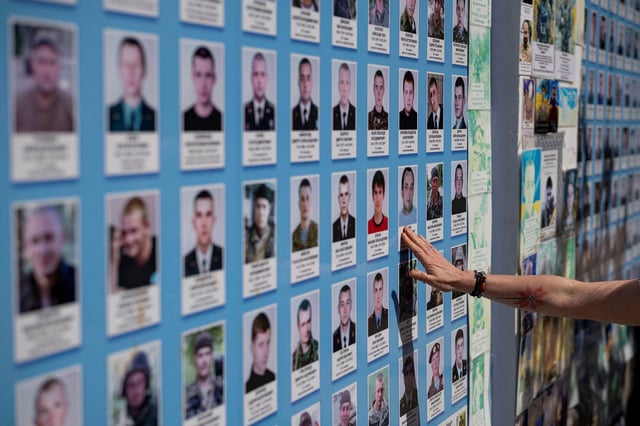A woman touches the portrait of a fallen Ukrainian soldier at a memorial wall as the country marks Defenders’ Remembrance Day,in Kyiv on August 29.