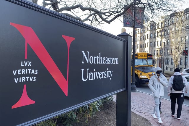 FILE - In this Jan. 31, 2019 file photo, pedestrians walk near a Northeastern University sign on the school's campus in Boston. (AP Photo/Rodrique Ngowi, File)