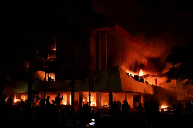 Protesters gather near the burning regional parliament building, during a protest after a motorcycle taxi driver died after being struck and run over by a police tactical vehicle during Thursday's protest against parliamentarians' allowances, in Makassar, South Sulawesi province, Indonesia, August 30, 2025. REUTERS/Iqbal Lubis