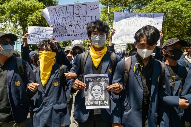 Un manifestant tient le portrait d'Affan Kurniawan, un taxi-moto écrasé par un véhicule de police dont la mort a provoqué des manifestations dans toute l'Indonésie, le 30 août 2025 à Surabaya, sur l'île de Java
