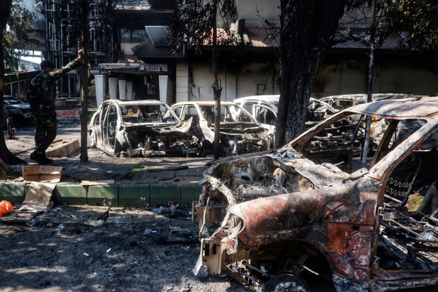 Des carcasses de voitures incendiées près du conseil provincial et local de Makassar, principale ville indonésienne des Célèbes du sud théâtre de manifestations qui ont dégénéré après la mort d'un taxi-moto écrasé par un véhicule de police, le 30 août 2025 

Cars and the Makassar City Council building, which were set on fire the previous night during a protest, are seen in Makassar, South Sulawesi, on August 30, 2025. At least three people were killed by a fire started by protesters at the council building in eastern Indonesia's Makassar city, a local official told AFP on August 30, after demonstrations across the country following the death of a motorcycle taxi driver hit by a police vehicle.