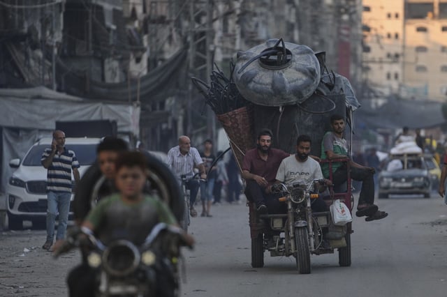 Displaced Palestinians fleeing northern Gaza Strip move with their belongings on a street in Gaza City, Friday, Aug. 29, 2025. (AP Photo/Jehad Alshrafi)