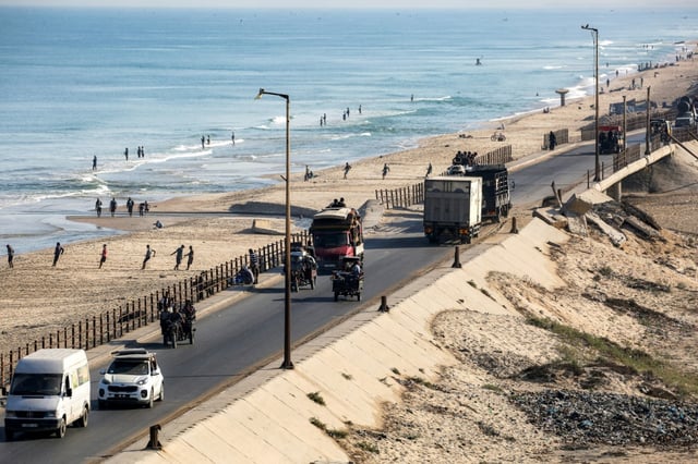 Des camions, des véhicules et des motos tirant des charrettes, certains chargés de Palestiniens fuyant le nord de la bande de Gaza, roulent sur la route côtière de Nousseirat (centre), en direction du sud du territoire, le 30 août 2025