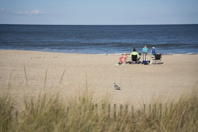 People relax at Rehoboth Beach, Del., on Wednesday, Aug. 27, 2025. (AP Photo/Mingson Lau)