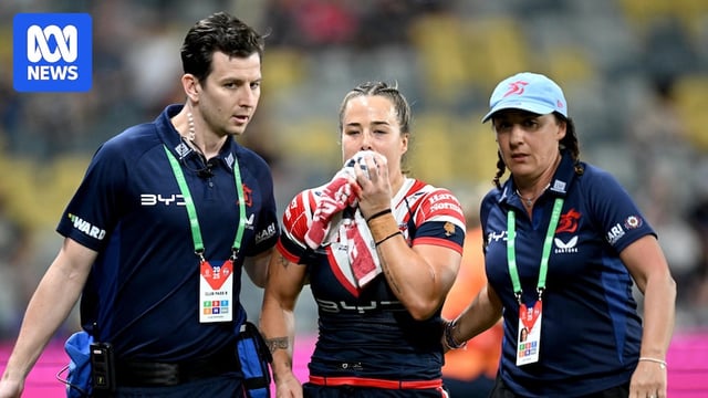 Isabelle Kelly holds a towel to her mouth after an injury in a Sydney Roosters NRLW game.