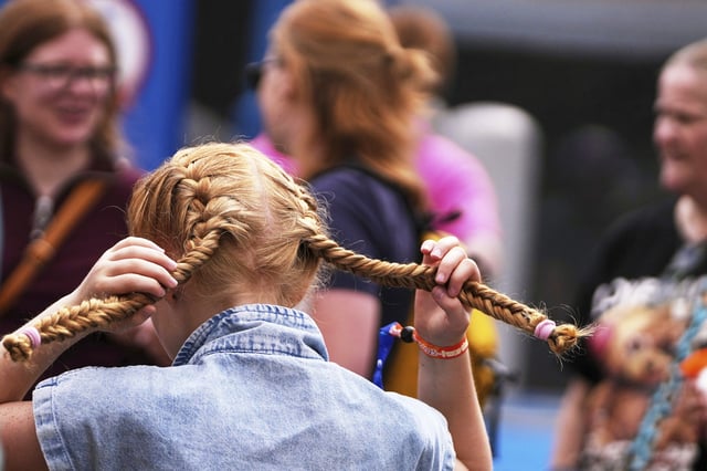 A young girl pulls on her braids during the Red Head Days festival in Tilburg, Netherlands, Saturday, Aug. 30, 2025. (AP Photo/Virginia Mayo)