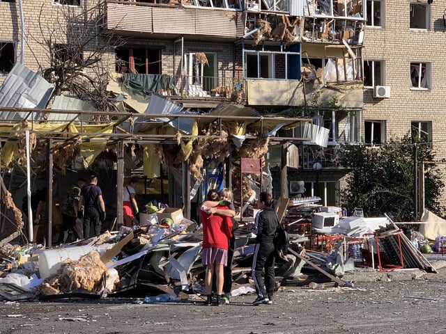 Local residents embrace each other next to a damaged residential building following an air attack in Zaporizhzhia on August 30, 2025, amid the Russian invasion of Ukraine. A 'massive' overnight Russian attack on central and southeastern Ukraine killed at least one person, authorities said on August 30, 2025, with homes and businesses damaged in multiple cities. (Photo by Marina Moiseyenko / AFP) (Photo by MARINA MOISEYENKO/AFP via Getty Images)          