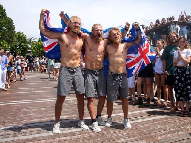 Scottish brothers (L-R) Lachlan, Jamie and Ewan MacLean celebrate as they arrive into Cairns in northern Queensland on August 30, 2025. The three Scottish brothers stepped ashore in Australia on August 30 after claiming a new record for rowing non-stop and unsupported across the Pacific Ocean, "over the moon" to be back on dry land. They set off in a carbon fibre dinghy from Lima in Peru in April for the 9,000 miles (14,500 kilometres) journey, enduring violent storms and sickness during their 139 days at sea. (Photo by Brian CASSEY / AFP) (Photo by BRIAN CASSEY/AFP via Getty Images)