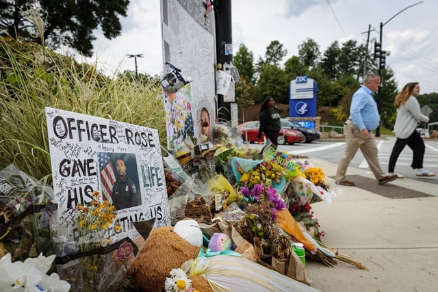 Pedestrians pass a memorial for officer David Rose at the CDC headquarters in Atlanta on Aug. 28, 2025. 