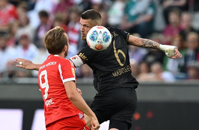 Soccer Football - Bundesliga - FC Augsburg v Bayern Munich - WWK Arena, Augsburg, Germany - August 30, 2025 FC Augsburg's Jeffrey Gouweleeuw in action with Bayern Munich's Harry Kane REUTERS/Angelika Warmuth