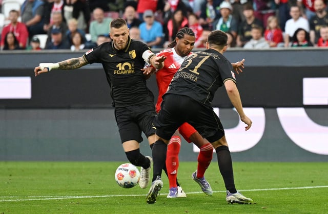 Soccer Football - Bundesliga - FC Augsburg v Bayern Munich - WWK Arena, Augsburg, Germany - August 30, 2025 FC Augsburg's Jeffrey Gouweleeuw and Keven Schlotterbeck in action with Bayern Munich's Serge Gnabry REUTERS/Angelika Warmuth