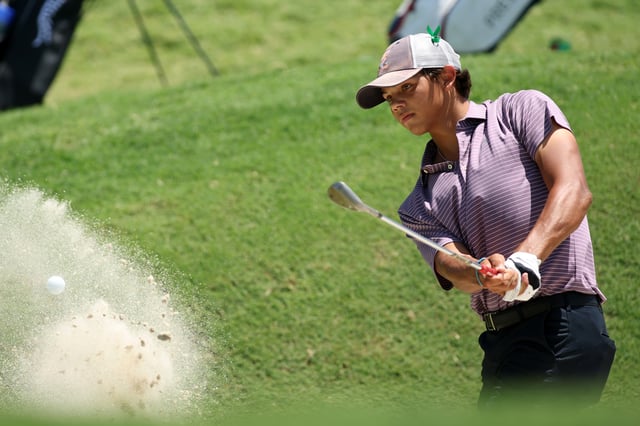 Charlie Woods of the United States chips out of a bunker on the tenth hole during the first round of the U.S. Junior Amateur at Brook Hollow Golf Club on July 21, 2025 in Dallas, Texas.