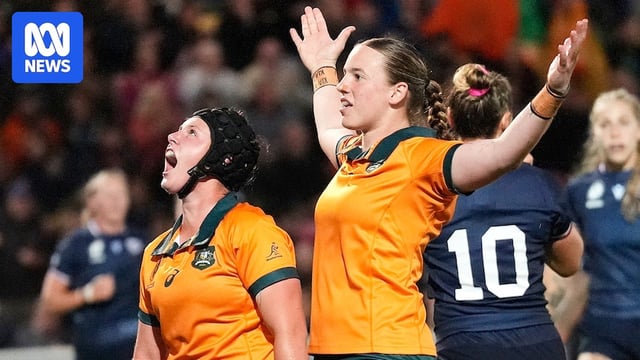 An Australian rugby player raises her arms in the air after scoring a try during a World Cup match.
