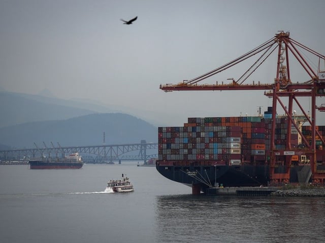 The paddle wheeler Constitution passes the container ship GSL Lydia docked at port, while sailing on the harbour as wildfire smoke hangs in the air, in Vancouver, on Thursday, Aug. 28, 2025.