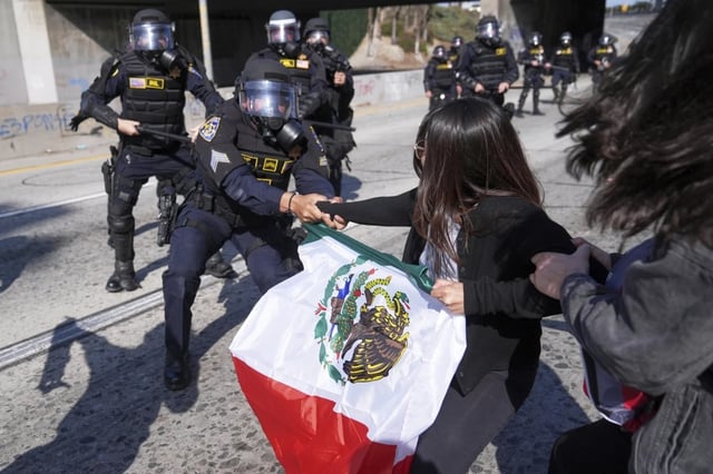 Manifestantes se enfrentan a la policía en la autopista 101, cerca del centro de detención metropolitano del centro de Los Ángeles, el domingo 8 de junio de 2025, tras la redada de inmigración de anoche. | Crédito: AP/Jae C. Hong