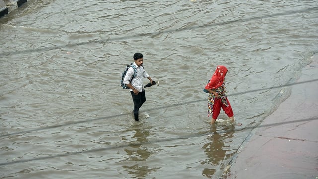 People wading through a waterlogged road in UP's Ghaziabad on Friday