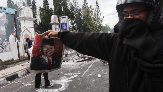 A protester holds a portrait of Indonesian President Prabowo Subianto during a demonstration in Mataram on Indonesia's Lombok Island.